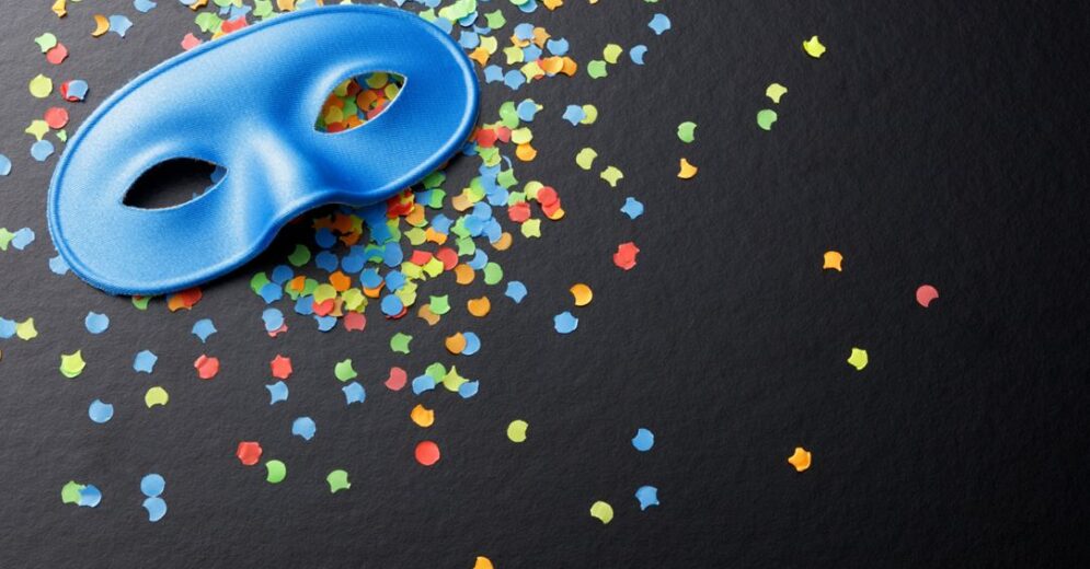 Venetiaans masker (blauw), liggend op een zwarte achtergrond op veelkleurige confettie