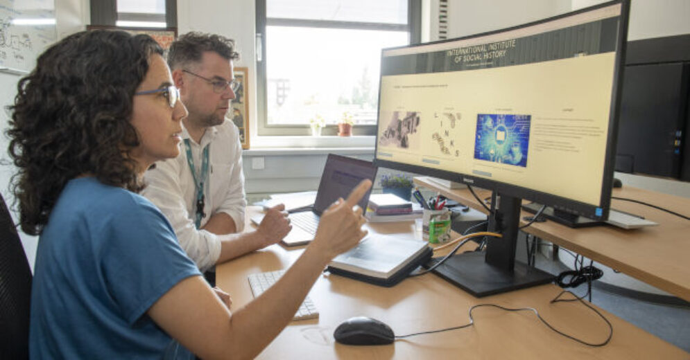 Twee personen achter een brede monitor terwijl ze dingen controleren